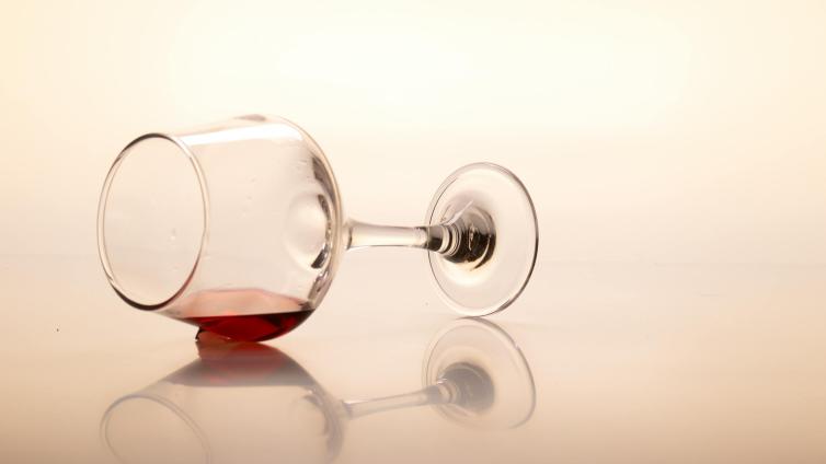 Glass of wine spilled on reflective surface. 